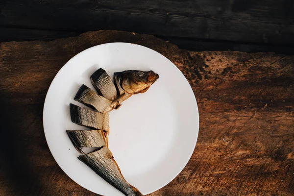 Pesce secco a fette su un piatto bianco su un tavolo di legno — Foto Stock