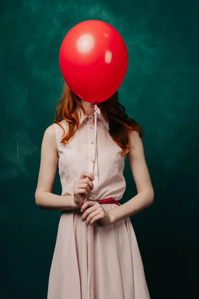 Mujer con un globo rojo sobre un modelo de vestido rosa de fondo verde —  Fotos de Stock
