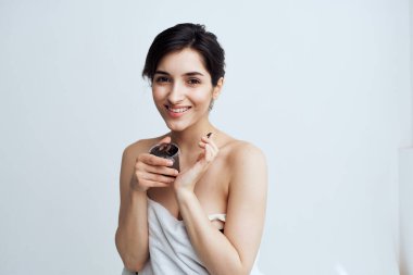 Güzel bir kadın çıplak omuzlarıyla cilt kremi temizler.