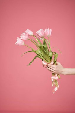 Bir buket çiçek ellerinde pembe arka plan hediye günü