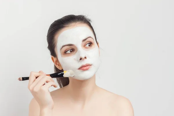 Bonita mujer aplicando crema de cepillo en la cara rejuvenecimiento del cuidado de la piel —  Fotos de Stock