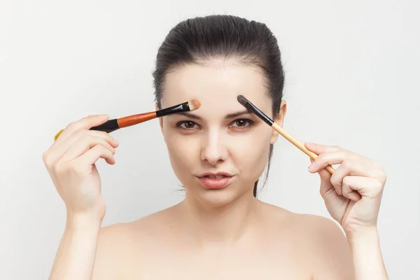 Brunette naked shoulders brush in hands applying cream — Stock Photo, Image