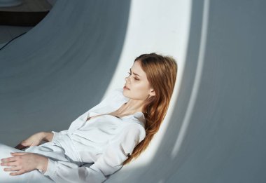 Beyaz elbiseli kızıl saçlı bir kadın Parlak bir oda manzaralı ve düşen bir gölge