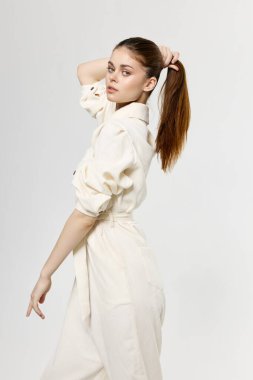 Kadın saçına dokunuyor ve şık kıyafetler giyiyor. Tulum tarzı kırpılmış manzara.