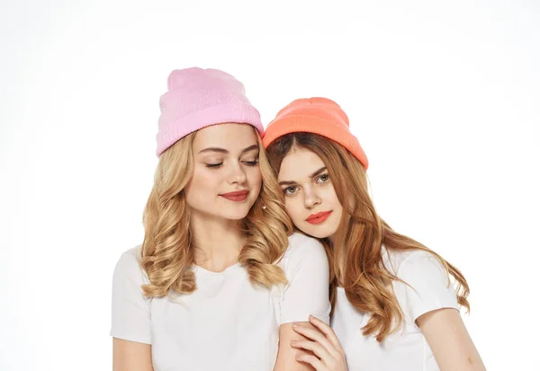 Deux amies dans des chapeaux multicolores étreintes style de vie vue recadrée arrière-plan clair — Photo