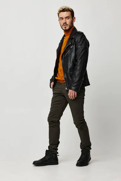 Man in merk kleding lederen jas oranje trui broek model — Stockfoto