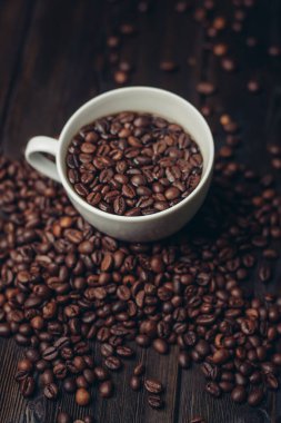 Tahta bir masanın üzerinde kahve taneleri ve aromatik bir içecek.