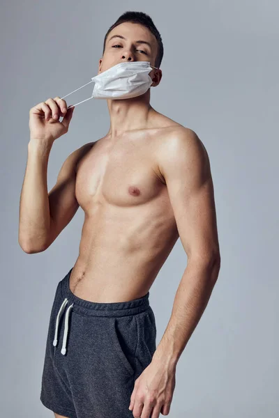 Atlétikai férfi izmos test orvosi maszk fekete rövidnadrág edzőterem — Stock Fotó