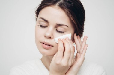 Esmer kadın, beyaz bir süngerle yüzünü siliyor.