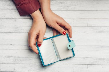 Kadın, ahşap bir masanın üstündeki kartvizit tutacaklarıyla şeffaf çarşafları inceliyor.