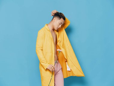 Sarı ceketli ve elinde çiçekle pembe pantolonlu romantik bir beyefendi.