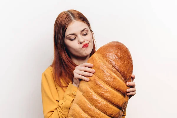 Mulher bonita com um pão em suas mãos em um fundo leve modelo de maquiagem lábios vermelhos — Fotografia de Stock