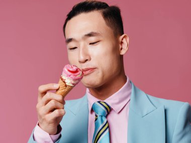 Takım elbiseli bir adam pembe arka plandaki dondurma külahına bakar.