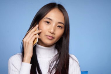 Asyalı görünümlü bir kadın telefon teknolojisiyle internette konuşuyor.