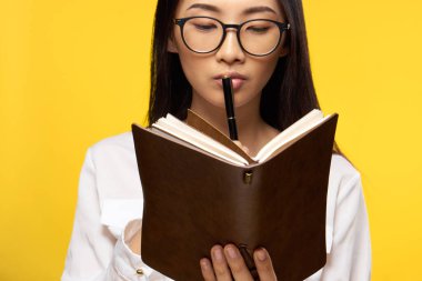 Güzel esmer. Not defterine bakıyor. Dudakların yanında zarif stil sarı arkaplan.