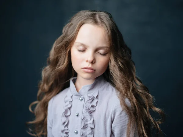 Girl in a blue dress on a dark background and curly cropped hair — Stock Photo, Image