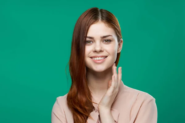 Vacker kvinna i rosa skjorta håller händerna nära ansiktet på grön bakgrund — Stockfoto