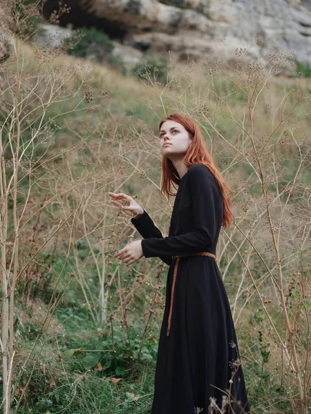 Femme dans la forêt dans une robe noire cheveux roux air frais nature — Photo