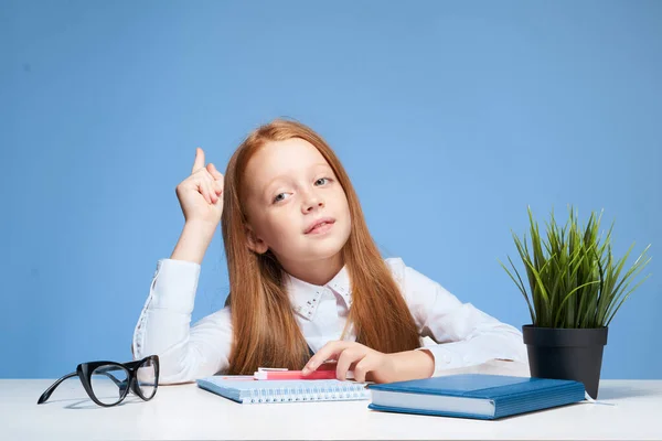 レッスン教育学校の勉強机の上の赤い髪の女の子 — ストック写真