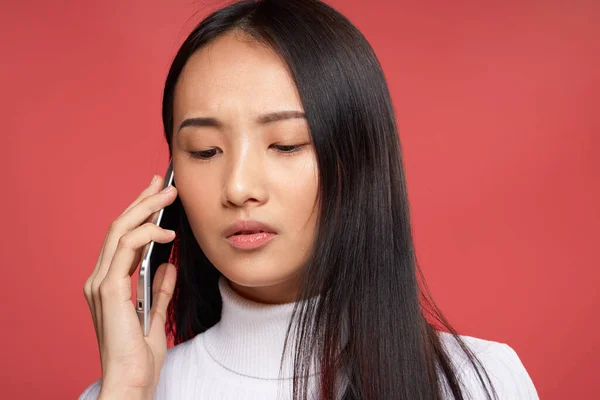 Симпатичная брюнетка, разговаривающая по телефону крупным планом на красном технологическом фоне — стоковое фото