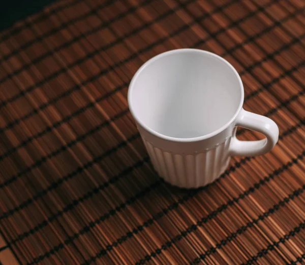 white mug on a wooden stand stands on the table top view
