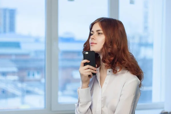Hübsche Frau im Hemd mit Telefon in der Hand — Stockfoto