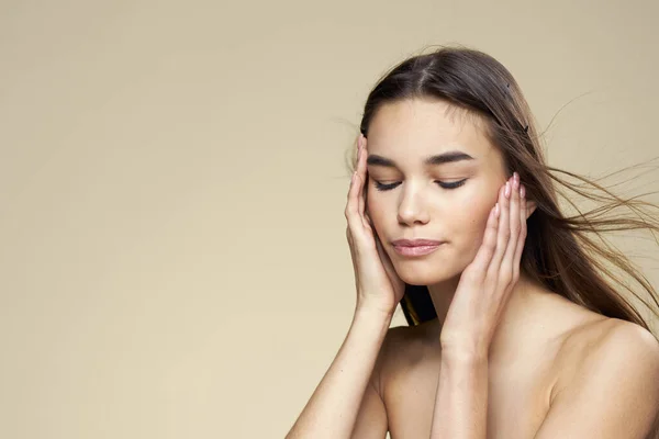 Flot kvinde nøgne skuldre kosmetik ren hud hårpleje beige baggrund - Stock-foto