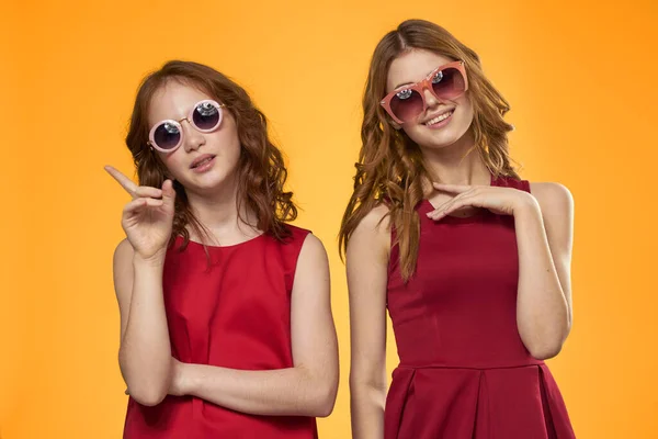 Glad mamma och dotter bär solglasögon livsstil vänskap familj gul bakgrund studio — Stockfoto