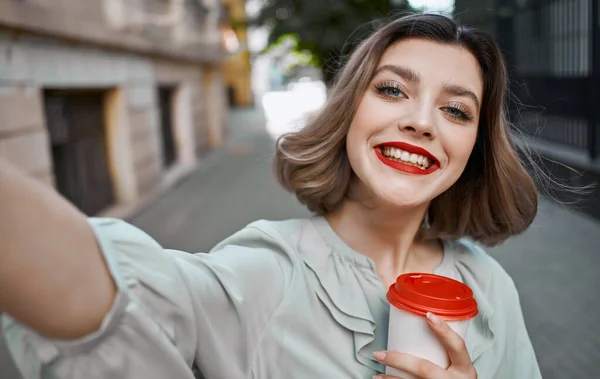Женщина с чашкой кофе в руке возле кирпичного здания и летом макияж красная юбка — стоковое фото