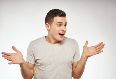 Tişörtlü yakışıklı adam elleriyle hareket ediyor. Duygularıyla stüdyo ışığı arka planında.