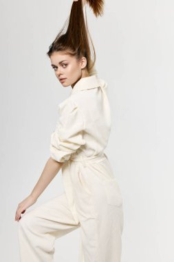 Kadınlar saçlarına elleriyle dokunur ve beyaz tulum giyer.