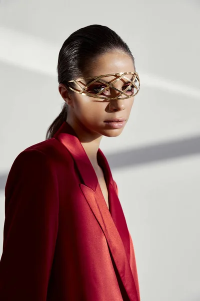 Portret van een brunette in een rode jas en accessoires voor haar ogen op haar gezicht — Stockfoto