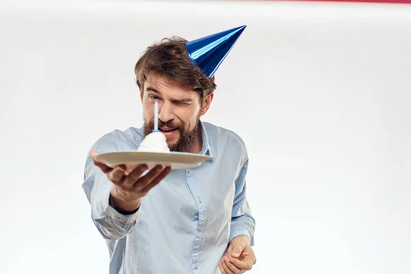 Un hombre con barba sostiene un pastel en su mano sobre un fondo claro cumpleaños — Foto de Stock