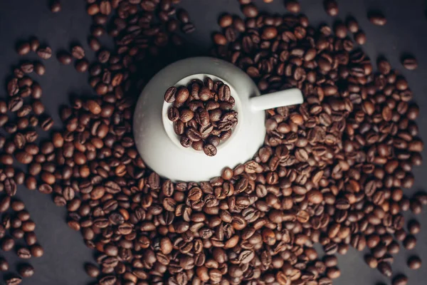 Ziarna kawy w filiżance i białe spodki szare tło zbliżenie — Zdjęcie stockowe