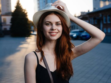 Gün batımında caddenin yanındaki binanın yanında siyah elbiseli zarif bir kadın.