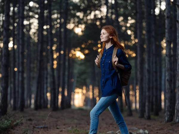 Γυναίκα ταξιδεύουν Μεταξύ των δέντρων στο δάσος το φθινόπωρο και το ηλιοβασίλεμα στο παρασκήνιο — Φωτογραφία Αρχείου