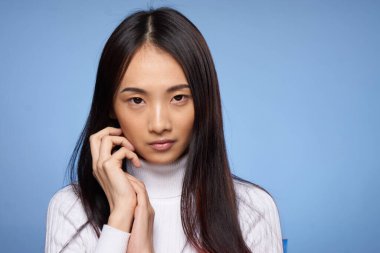 Siyah saçlı, beyaz kazaklı güzel bir kadın elleriyle temiz cilt kozmetolojisi yapıyor.