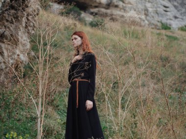 Ormanda siyah elbiseli bir kadın. Kızıl saçlı. Temiz hava.