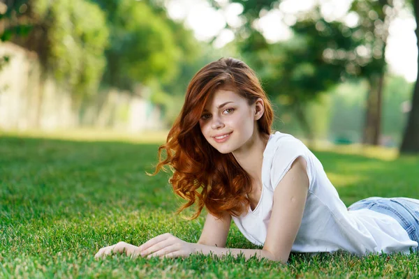 Rothaarige Frau liegt im Park auf dem Rasen an der frischen Luft — Stockfoto