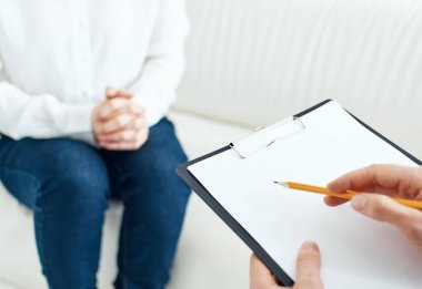 Belgeleri olan bir iş adamı ve bir kadın, parlak bir odada, kanepede oturuyor.