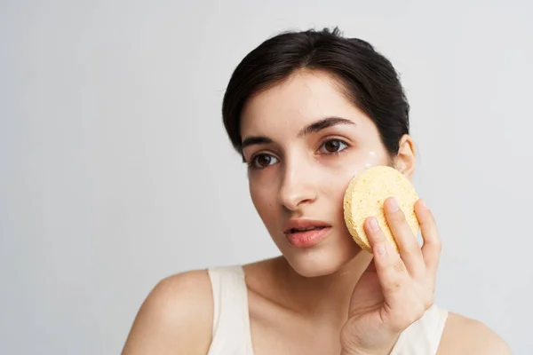 Mulher bonita com esponja limpa cuidados faciais close-up — Fotografia de Stock