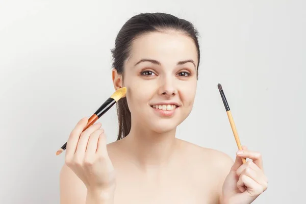 Cheerful woman with bare shoulders brushes in hands sponge cosmetics — Stock Photo, Image