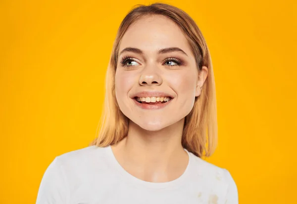Mulher loira feliz ri em um fundo amarelo em uma camiseta branca — Fotografia de Stock