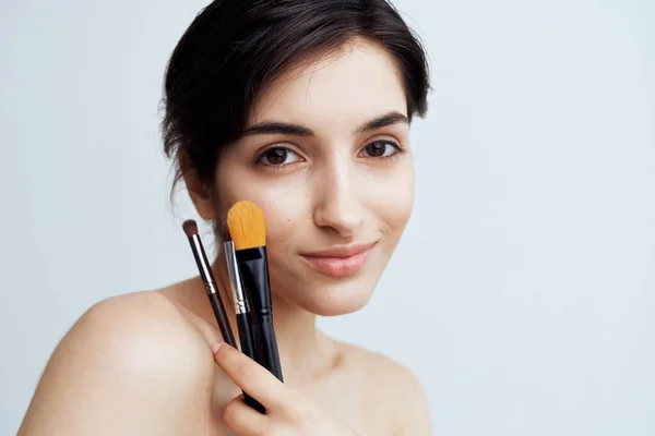 Pretty brunette naked shoulders shower makeup brushes cosmetics close-up — Stock Photo, Image