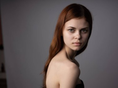 Gri arkaplanda kadın portresi. Çekici, kızıl saçlı, kırpık saçlı.