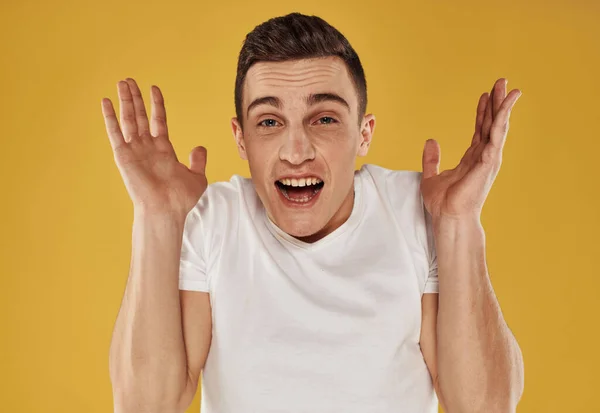 Een energieke man in een wit T-shirt raakt zijn hoofd met zijn hand op een gele achtergrond — Stockfoto