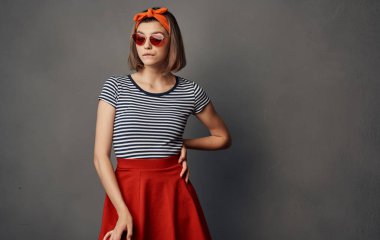 Turuncu saç bandı kırmızı etek modasında gözlüklü güzel bir kadın.