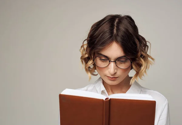 Femme d'affaires avec cahier ouvert dans ses mains et lunettes sur son visage, chemise blanche — Photo