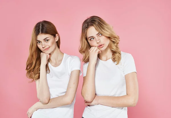 Två flickvänner i vita t-shirts trötta look semester livsstil rosa bakgrund — Stockfoto