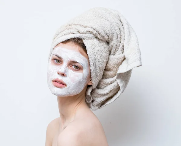 Bonita mulher grooming branco máscara facial e toalha na cabeça — Fotografia de Stock